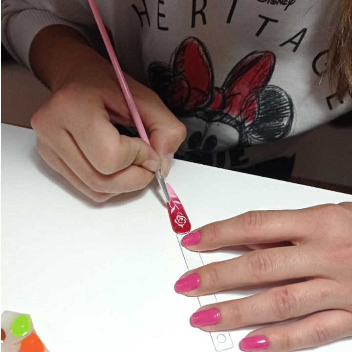 Alumna haciendo flores de nailt art en mostrarios de uñas