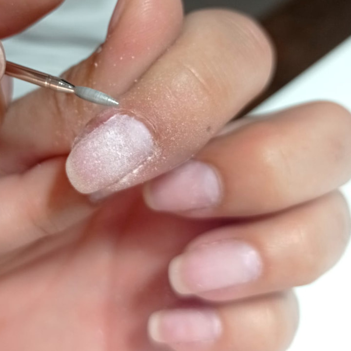 Estudiante realizando procedimiento de manicura rusa en sus manos.