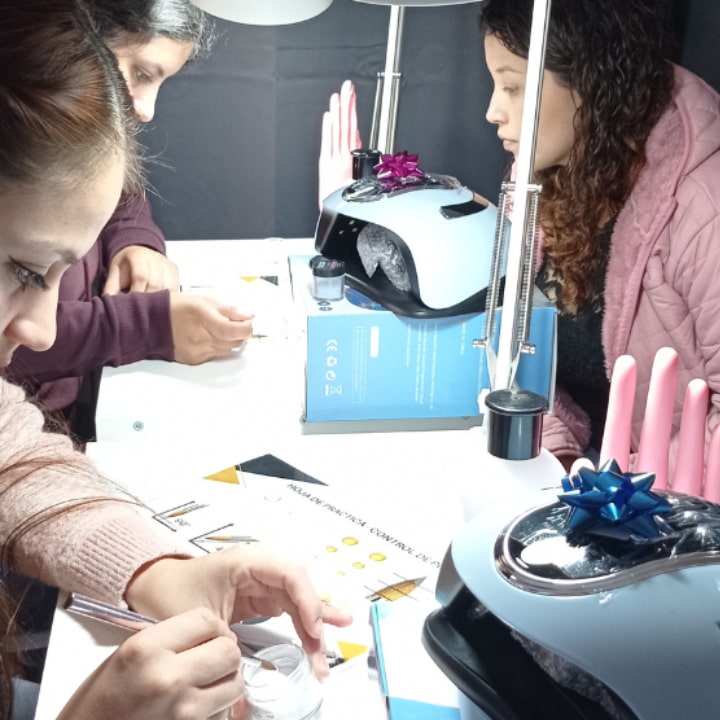 Estudiantes practicando el control de perlas acrílicas con la profesora liz