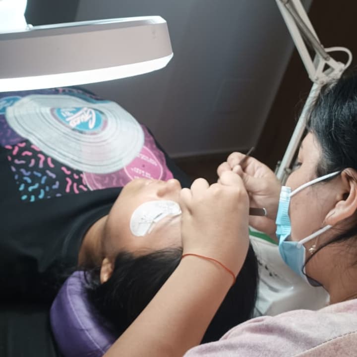 alumna haciendo práctica del curso de extensiones de pestañas