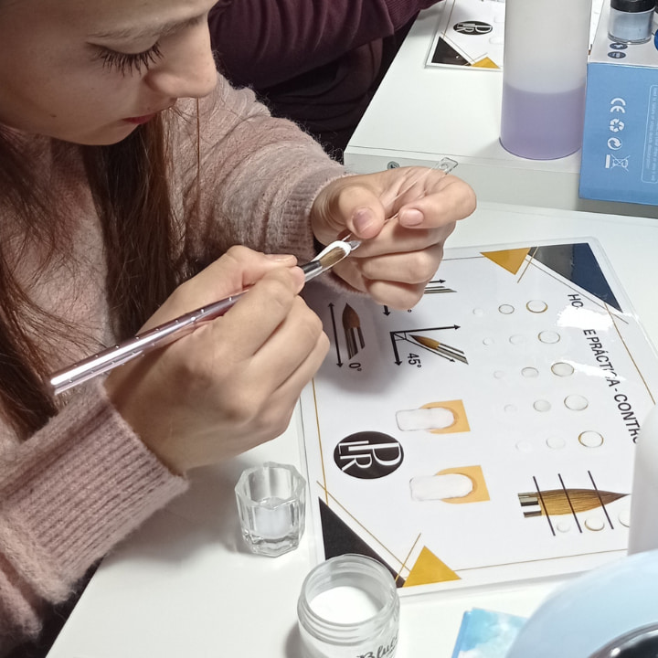 Estudiante haciendo práctica de control de perlas de uñas acrílicas